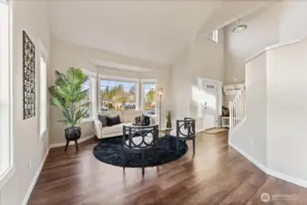 The living room is light and bright, filled with natural light and enhanced by high ceilings that create an open, airy feel.