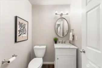 The updated half bath features new lighting, a marble vanity, and a new commode, adding a fresh and modern touch.