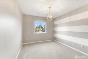 This bedroom features adorable striped walls and a charming chandelier, adding a sweet and playful touch.