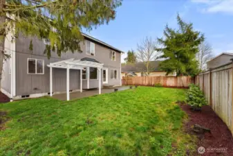 The backyard is level and fully fenced, featuring a patio and pergola that create an ideal space for entertaining, relaxing, or play.
