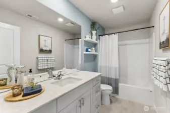 Hall bathroom with modern quartz countertops and soft close doors on shaker style cabinets. Actual home is under construction. Colors, materials, and features may vary. See site agent for details.