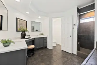 Get ready in this large en-suite bathroom complete with double-sink vanity and sitting spot between sinks, walk-in tile shower with bench seat, enclosed toilet space.