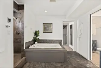 Primary bedroom en-suite with tile shower and soaking tub - access to the large custom walk-in closet.