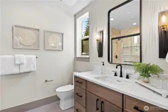 Main floor guest bathroom features a wide vanity with two sets of drawers and step-in shower with shampoo niche...plus, a built-in linen cabinet tucked out of the way behind the door.