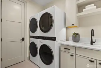 Laundry room with double stack LG front-loading washers and dryers. Upper and lower storage cabinets, slab quartz countertop, utility sink, open shelving with under counter lighting, and a linen closet.