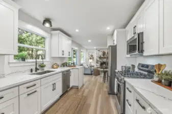 Remodeled kitchen showcasing white shaker cabinetry and quartz countertops, seamlessly connecting to the family room and dining area.