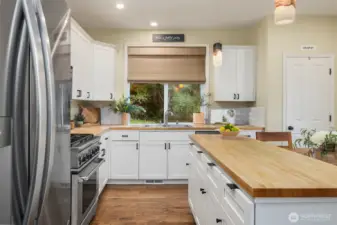 Butcher block counter tops and newly refinished white cabinetry elevate this roomy main floor kitchen.