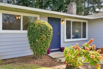 A closer look at the entry reveals a bold front door framed by landscaped beds. The covered approach creates a warm first impression and highlights the home’s inviting style.