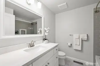 The full bathroom on the main level is finished with a wide vanity, framed mirror, and updated fixtures. Clean design and ample counter space add to its appeal.