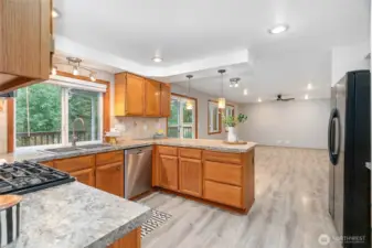 Spacious remodeled kitchen with upgraded appliances, tile backsplash, new sink, faucet, garbage disposal, and lighting elements.