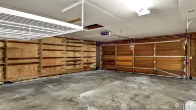 Large two car garage with storage shelves.