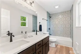 Primary En Suite Bath w/Luxurious Dual Sink Vanity, Laminate Floors and Custom Tile Shower Surround.