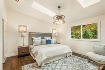 Primary suite with vaulted ceiling, skylights, serene views, and remodeled bath.