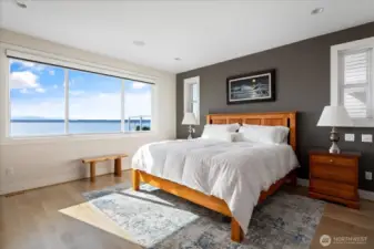 This luxurious main-floor primary suite is a private waterside retreat. A warm fireplace sets the tone for relaxation, while French doors lead directly to the waterside hot tub, allowing you to enjoy the sparkling Puget Sound views in ultimate comfort and style.