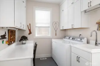 his well-appointed mudroom and laundry space combines practicality and style. Floor-to-ceiling built-in storage keeps everything organized, while a generous laundry sink handles tasks with ease. A built-in desk adds a convenient workspace, making this area both highly functional and beautifully designed for everyday living