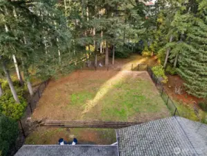Fully fenced backyard with wooded greenspace beyond.