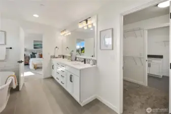 Primary Bath with Direct Laundry Access  This primary bathroom showcases a dual-sink vanity with quartz countertops, matte black fixtures, and a full-width mirror that enhances light and scale. Clean tile lines and durable flooring reinforce the spa-inspired design while maintaining everyday functionality.    A unique pass-through layout connects the en suite to the walk-in closet and onward to the laundry room, offering direct laundry access for added convenience. Located in Bothell near Canyon Park amenities, this thoughtful configuration reflects the innovation and quality associated with modern luxury new construction within the Northshore School District.    These photos are from a past Robinson Plan at a different community, so overall plan, colors, building orientation, finishes, home outlook, and other details can and WILL vary. All photos, renderings, site maps, and floorplans are for visualization purposes only.