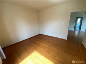 View of bedroom looking into living room. Notice the original wood flooring, still in really good shape.