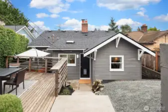 Access to home from the alley, detached garage and parking pad. Large deck to the left, gravel seating area (perfect for firepit?) to the right.