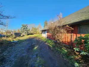 Left side of home with gravel access to garage and backyard