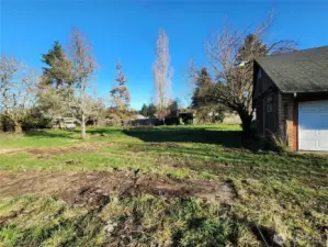 Left side view of spacious, partially fenced backyard