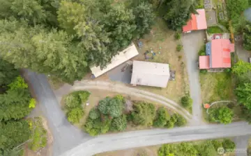 Aerial view of the property shows its spacious lot, wooded perimeter, and private setting on a quiet corner lot. Excellent layout for privacy and potential outdoor amenities.