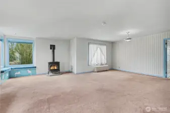 Spacious living room with a gas stove, large windows, and original trim, offering a bright gathering space ready for modernization or restoration.