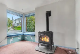 Charming bay-window nook with built-in seating and a gas stove, showcasing classic features and providing a warm, character-filled corner with room for future improvements.