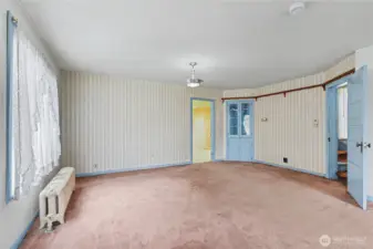 Light-filled dining or flex room with vintage wallpaper, built-in storage, and original architectural details—ideal for buyers seeking a project with strong bones and period charm.