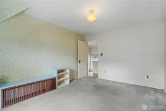 Cozy room featuring vintage wallpaper, sloped ceilings, and built-in radiator cover, offering classic character and a solid foundation for future updates or creative redesign.