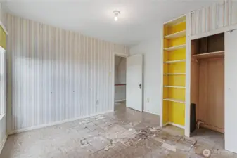 Third bedroom with built-in shelving, and exposed closet area, providing a clear opportunity for restoration or reconfiguration to suit modern needs.