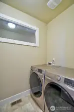 Upstairs utility room has front load washer/dryers and deep utility sink, cabinets, counter and clothes bar.