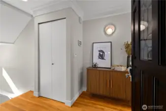 Entryway with coat closet. To the left are stairs to the garage and large storage room.