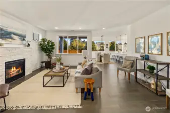 Great Room  The great room showcases open concept living with clean architectural lines and expansive rear windows that draw in natural light and frame the private backyard setting. A modern fireplace with textured surround anchors the space, creating warmth and visual contrast against wide plank flooring. The layout flows seamlessly into the kitchen and dining areas, supporting effortless gathering and everyday functionality. Designed for contemporary living in Bothell’s Canyon Park area, this space reflects the elevated finishes and thoughtful flow expected in luxury new construction within the Northshore School District.    These photos are from a past Robinson Plan at a different community, so overall plan, colors, building orientation, finishes, home outlook, and other details can and WILL vary. All photos, renderings, site maps, and floorplans are for visualization purposes only.