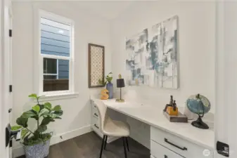 Main Level Pocket Office  This main level pocket office delivers a dedicated workspace without sacrificing the home’s open flow. A built-in desk with quartz surface and integrated cabinetry provides clean, functional storage, while a large window brings in natural light to create a bright, focused setting. The efficient footprint supports productivity while maintaining architectural simplicity.    Located in Bothell’s Canyon Park neighborhood, this signature design element reflects the thoughtful planning associated with contemporary new construction. The flexible workspace enhances everyday livability within a modern home served by the Northshore School District.    These photos are from a past Robinson Plan at a different community, so overall plan, colors, building orientation, finishes, home outlook, and other details can and WILL vary. All photos, renderings, site maps, and floorplans are for visualization purposes only.