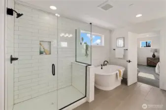 Primary Bathroom  The primary bathroom blends clean design with spa-inspired comfort. A tiled walk-in shower with glass enclosure and built-in niche offers streamlined functionality, while the freestanding soaking tub creates a defined relaxation zone beneath natural light. Matte black fixtures add contrast against the bright, contemporary finishes.    Located in Bothell, Washington near Canyon Park amenities, this en suite reflects the elevated craftsmanship associated with high-end new construction. The thoughtful layout supports daily routine and retreat within a modern home served by the Northshore School District.    These photos are from a past Robinson Plan at a different community, so overall plan, colors, building orientation, finishes, home outlook, and other details can and WILL vary. All photos, renderings, site maps, and floorplans are for visualization purposes only.
