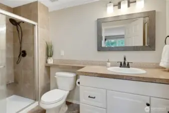 Primary bathroom has plenty of countertop space, storage, a glass shower door with a tiled shower surround, and a solar tube brings lots of natural light!