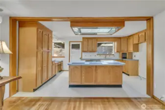 Kitchen with peninsula seating and open sightlines. There is a desk area to the left and large pantry for additional storage.