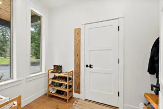 Mud room next to entry. Has bench and coat hangers to right, entry to garage.