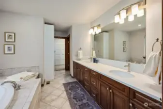 Inside the primary suite bathroom, find pretty tile floors and long length vanity across from the tiled in bathtub and window.