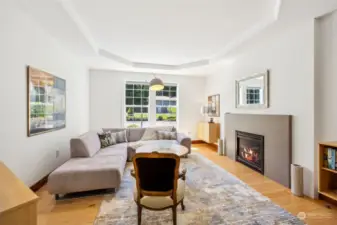 Dramatic tray ceiling over the contemporary tiled gas fireplace in the living room creates a special place for spirited conversations or a cozy night in front of the fire.