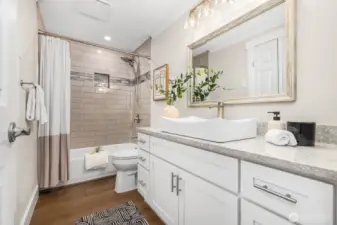 The updated full bathroom features chic subway tile, a modern vanity with generous storage, and brushed nickel finishes for a clean, timeless look.