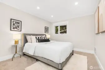 A bright and comfortable guest bedroom with neutral walls, plush carpet, and cozy natural light—ready to welcome family or friends.