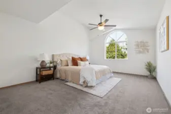 There is ample room in this well appointed primary bedroom with vaulted ceilings.