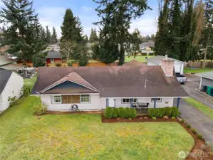 Aerial front view highlights the home’s attractive curb appeal, covered porch, and spacious front yard.