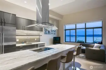 A show-stopping kitchen features a massive slab granite island with stainless vent hood.