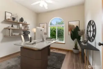 Virtually staged bedroom (staged here as an office) with hardwood flooring and a half-moon, formerly called a lunette, window. Closet with built-in custom shelving and storage is to the left of the photo and ceiling fan.