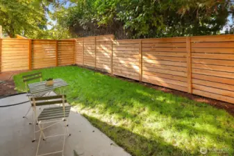 Fully fenced and level backyard with mature trees and patio.