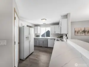 Kitchen view from the other side showing the gorgeous quartz countertops and the breakfast bar! So much counterspace for meal prep, making cookies, and don't forget homework time on the breakfast bar.