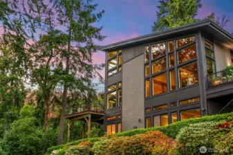 Framed by towering evergreens and vibrant gardens, the home’s bold geometry and rich materials create a striking profile that is both modern and warm.